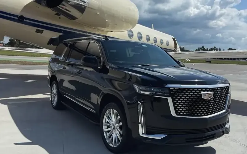 Black Cadillac Escalade waiting beside a private jet for an airport pickup
