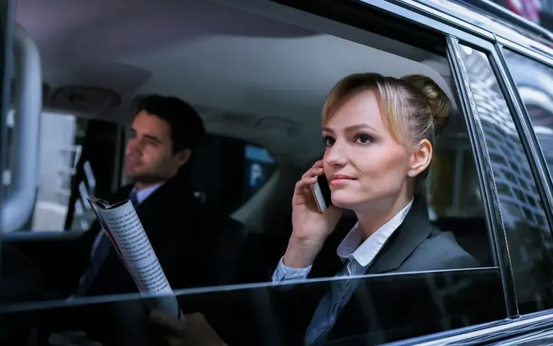 Business passengers in the back seat of a chauffeured sedan