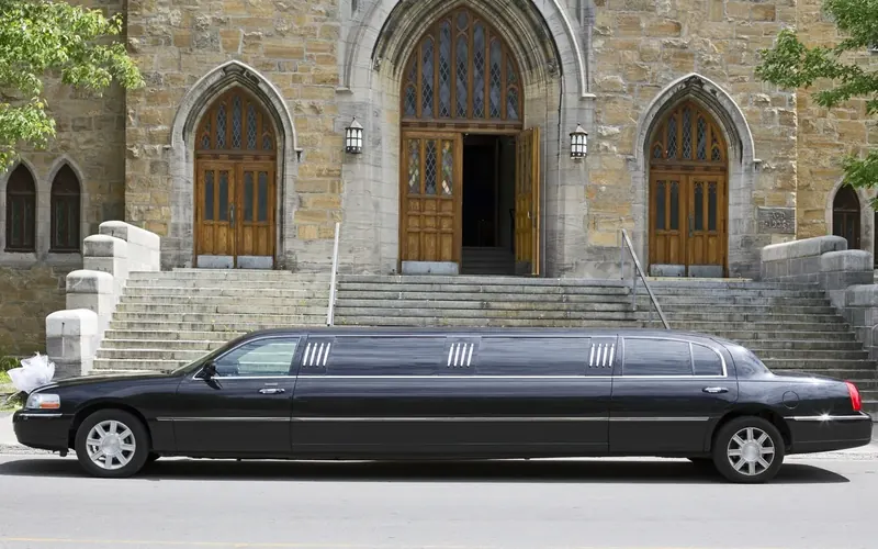 Black stretch limousine parked outside a stone church